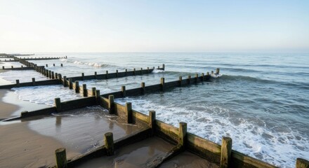 Fototapeta premium Coastal Groynes and Sea Waves - A Serene Beach Scene.