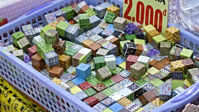 A Blue Plastic Basket Filled with Assorted Minecraft Style Pixel Art Cube Toys for Sale