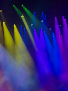 abstract stage lights and beams at concert in yellow, blue and purple colors