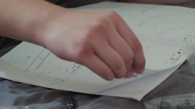 Man assembling a new wardrobe in a living room while checking printed furniture assembly instructions.