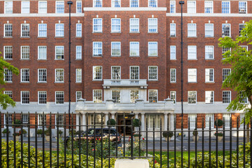 Traditional red brick residential apartment building facade in London with iron fence © SellStock