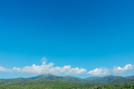Blue sky with white clouds over mountain peak with copy space for text.