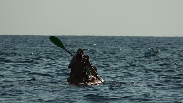 Kayaking rowing ocean three people sit on a paddleboard paddling at sea during summer leisure activity adventure
