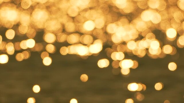 Golden bokeh water reflecting the setting sun with shimmering light patterns creating a peaceful and abstract background texture