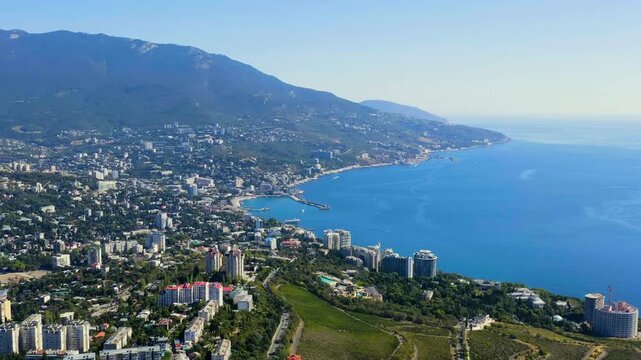Yalta, Crimea. Panorama of the city in sunny weather. Embankment and port. Drone footage