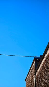 Minimalist low angle view of a brick wall roof under a bright clear blue sky, copy space concept for modern architecture design.   