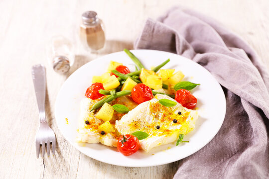 Baked cod fish fillet with roasted potatoes green beans and cherry tomatoes