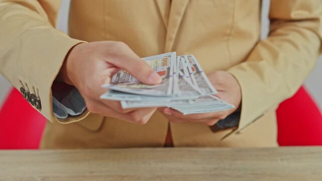 Close up of businessman counting cash and handing over stack of hundred dollar bills