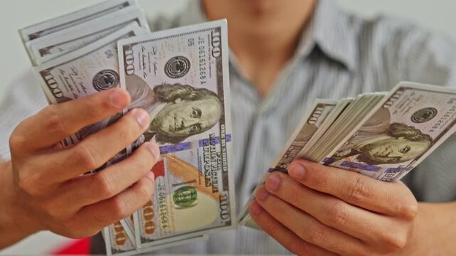 Close up of hands counting thick stacks of United States one hundred dollar bills