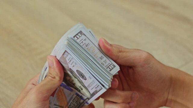 Close up of Hands holding and counting big stack of cash money dollars