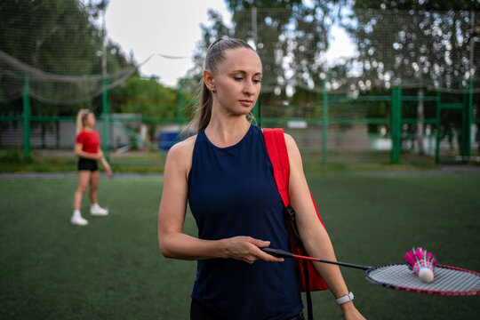 Young woman holding racket horizontally with shuttlecock on it. Balance skill and badminton equipment display.