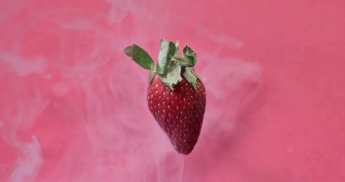 Red ripe strawberry floating on red background smoke vape mist flowing motion