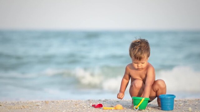 Kid collects shells and pebbles in the sea on a sandy bottom under the summer sun on a vacation
