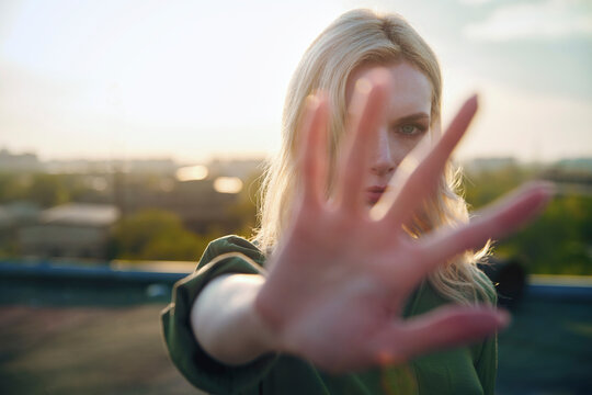 Serious blond woman showing stop gesture at sunset