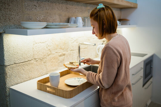 Woman preparing breakfast toast in modern kitchen at home in morning