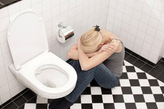 Despaired anorexic young woman at the toilet