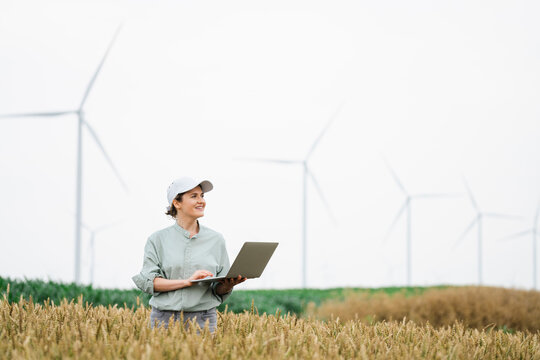 Happy farmer standing with laptop at field