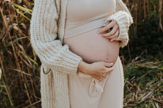 Expectant mother touching bare pregnant belly outdoors in autumn
