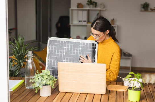 Young freelancer explaining with solar panel over laptop at desk