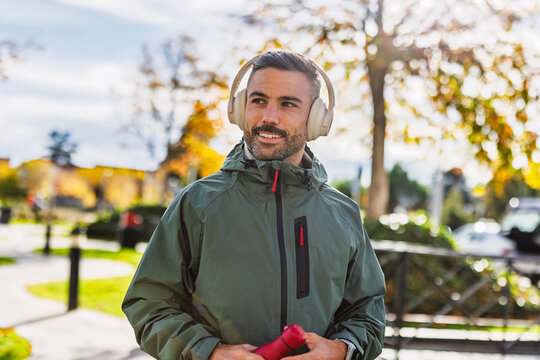 Smiling man with headphone in city park after street workout