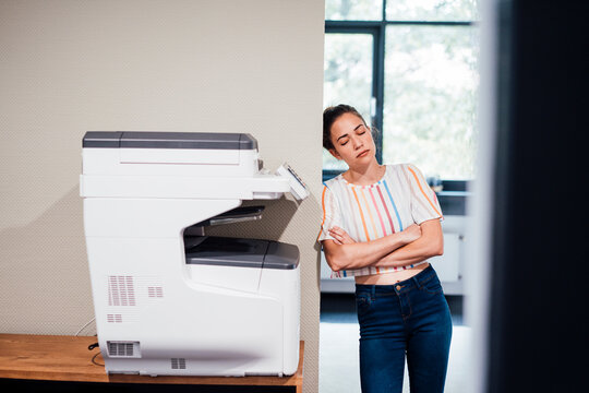 Businesswoman with eyes closed leaning on wall in office