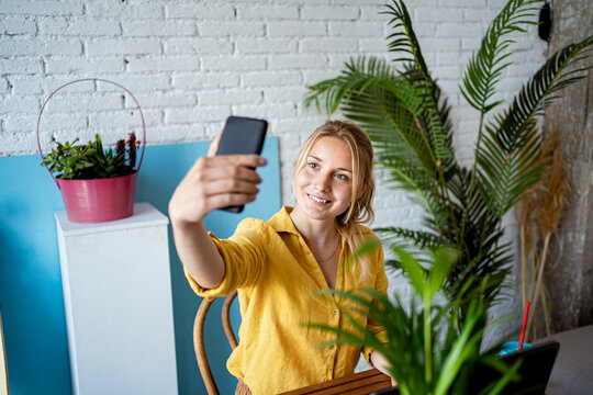 Businesswoman taking selfie through smart phone at home office