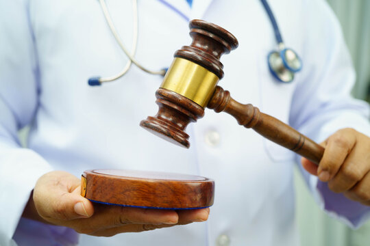 Asian doctor holding court hammer for and crime law justice, forensic medicine.