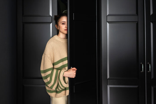Woman staring while opening door of closet