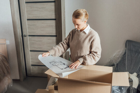 Young woman checking floor plan on cardboard box
