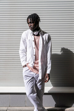 Young man with hand in pocket standing in front of shutter