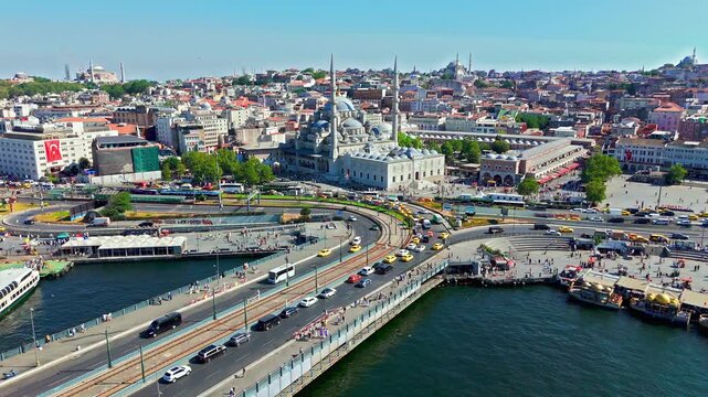 Drone view over Galata Bridge and the surrounding Eminonu area, showing the Yeni Mosque, busy roads, the shoreline, and the dense cityscape of Istanbul.