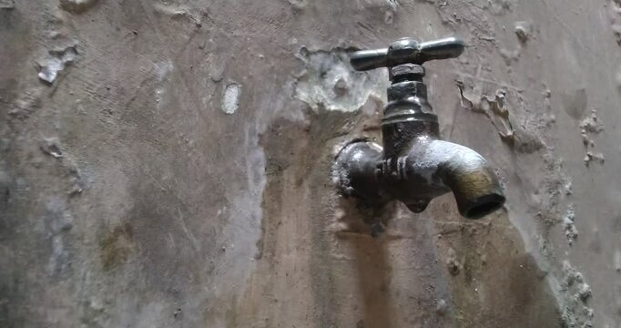 Old Rusty Faucet on a Textured Wall.