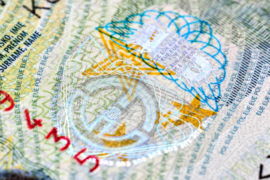 Macro closeup of Polish Schengen visa sticker in passport showing intricate holographic security features, official watermarks, guilloche patterns, and microprinting for identity authentication.