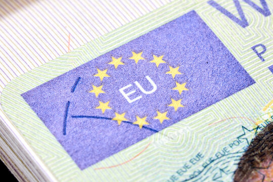 Fragment of Polish Schengen visa sticker inside travel passport showing security features like holographic European Union stars, intricate guilloche patterns, and official microprint for border entry.