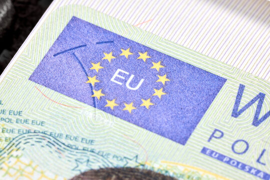 Fragment of Polish Schengen visa sticker inside travel passport showing security features like holographic European Union stars, intricate guilloche patterns, and official microprint for border entry.