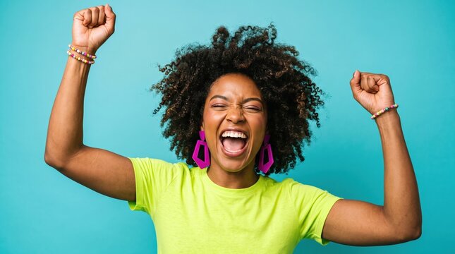 Excited young woman with afro hair cheering with raised arms against a blue background cheering celebrating lifestyle