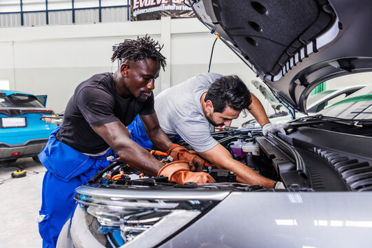 Professional EV technicians collaborating to diagnose and resolve an electrical problem in a modern electric vehicle service workshop.