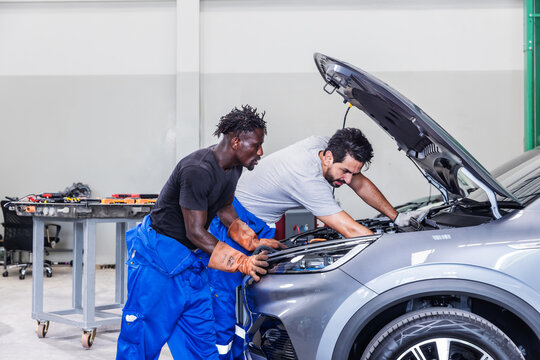 Professional EV technicians collaborating to diagnose and resolve an electrical problem in a modern electric vehicle service workshop.