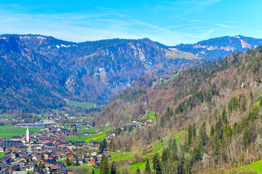 Malerische Dorfansicht von Bezau im Bregenzerwald mit markantem Kirchturm vor bewaldeten Bergh&auml;ngen, Vorarlberg, &Ouml;sterreich