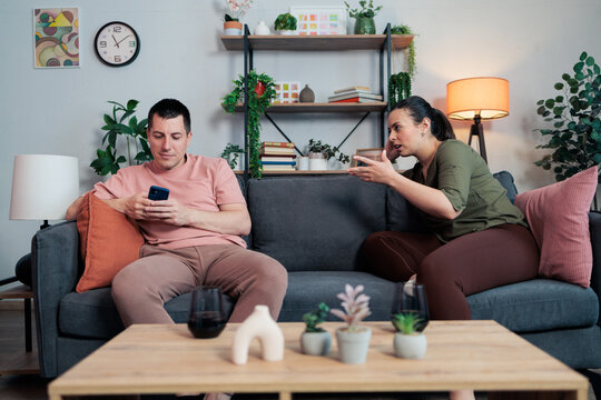 Couple having conflict with man phubbing on smartphone