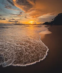 Dramatic golden sunset seascape over a tropical beach with gentle washing waves. © artrachen