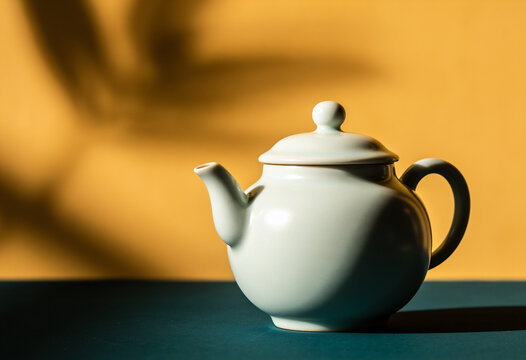 A white teapot rests on a dark surface