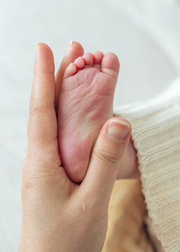 Mother holding newborn baby feet close up