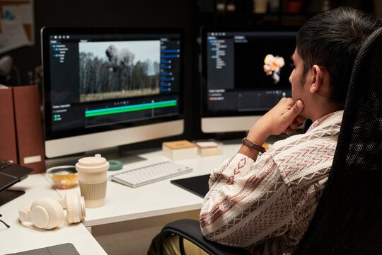 Young man reviewing video editing timeline on desktop monitors, planning postproduction workflow. Ideal for content creation, creative agency, digital media marketing