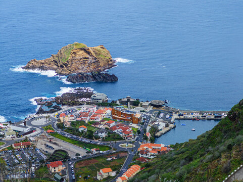 A breathtaking high-angle view of the seaside town of Porto Moniz stretching along the rugged Atlantic ocean coast, Madeira, Portugal.