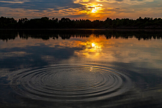 Ripples in a lake reflecting a colorful sunset at Fountain Lakes Park in St. Charles, Missouri 