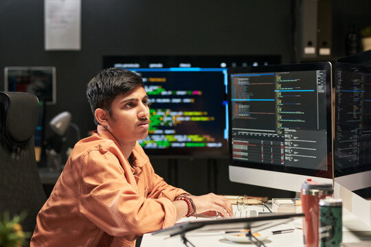 Young developer coding at desktop computer, monitoring software interface and debugging program in office. Ideal for technology careers, app development, IT services marketing