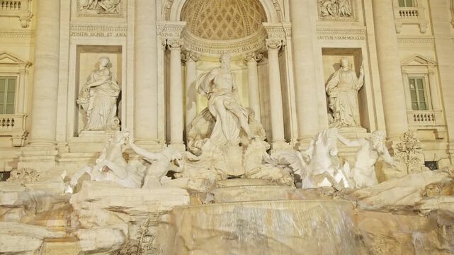 Baroque masterpiece of the trevi fountain in rome with flowing water. A famous and historic landmark in italy illuminated in the evening