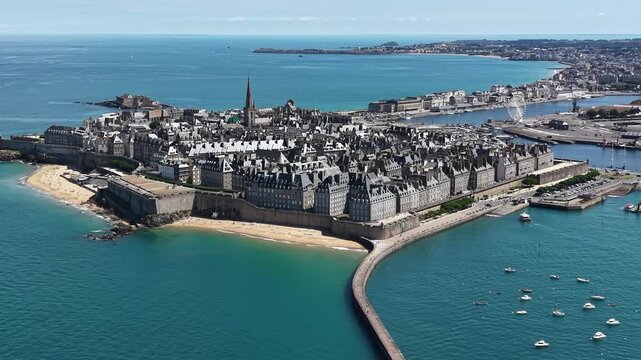 Cinematic slow orbit drone aerial of Saint-Malo, gracefully circling the iconic walled city while revealing the historic granite ramparts, sandy beaches, turquoise waters of the Emerald Coast
