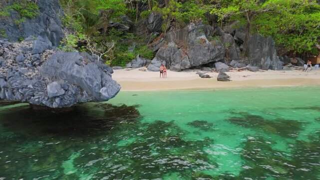 Drone pulls back from a model released couple to reveal a small island beach